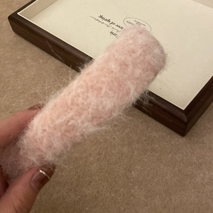 Close-up of a plush pink headband with soft fluffy faux fur texture held in hand