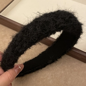 Close-up of a thick black plush headband showing soft shaggy texture and inner lining