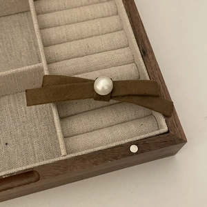 French style brown suede bow hair clip with a large pearl accent on a wooden jewelry box