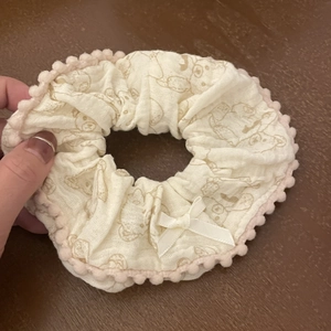 Cute beige scrunchie with pink pom-pom trim, ribbon bow, and bear print design