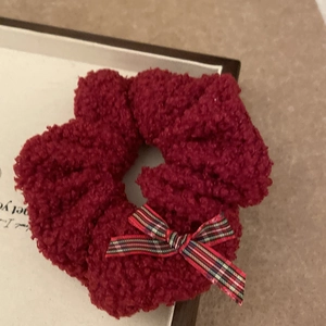 Detail of red fleece scrunchie with a tartan plaid bow accent and soft texture