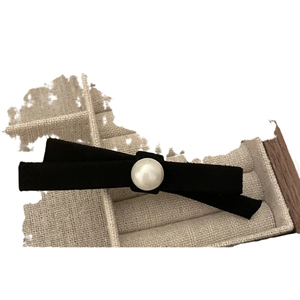 Elegant French black velvet bow hair clip featuring a large center pearl on a jewelry box