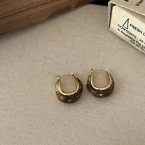 Vintage amber U-shaped earrings with gold metal frame on rustic linen background
