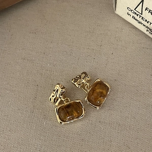 Retro amber resin earrings with golden hammered metal finish on a beige linen background