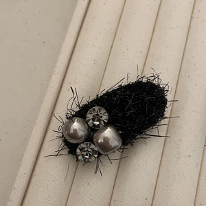 Detailed view of the black textured fabric hair clip with elegant pearls and metal beads