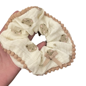 Cute cream scrunchie with brown bear print, pom-pom trim and a delicate ribbon bow