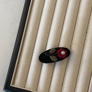 Vintage embroidered red flower hair clip with pearl detail on black velvet display
