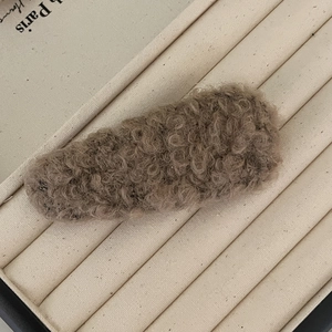 Gros plan sur la texture de la barrette en peluche kaki effet laine de mouton bouclée