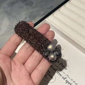 Elegant brown knit hair clip with grey pearls and rhinestones on a white background