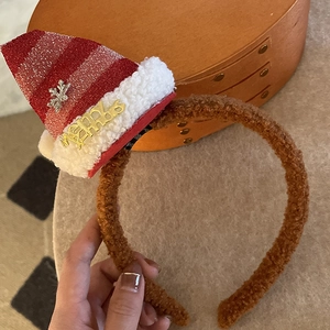 Detail of Christmas headband with plush brown fabric and a mini striped Santa hat with Merry text