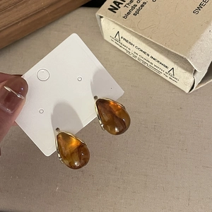 Detailed macro view of amber teardrop resin earrings with elegant gold metal trimming
