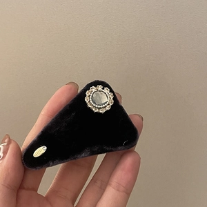 Detailed close-up of a velvet triangle hair clip featuring a vintage rhinestone and gold tag