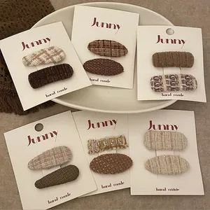 Détail de pinces à cheveux à carreaux marron et cœurs tricotés sur cartes blanches