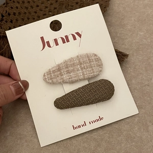 Gros plan de barrettes en tweed beige et tissu tissé vert olive sur carte d'affichage