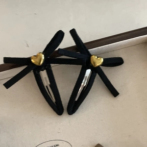 Makro-Detail von schwarzen Samt-Haarschleifen mit goldenem Herz-Metallbesatz