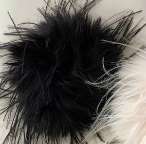 Dettaglio di elastici per capelli in piume nere e crema con fibre a trama morbida