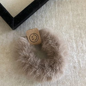 Gros plan sur chouchou en peluche café clair avec étiquette en cuir souple souriant