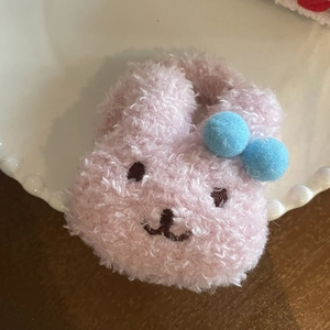 Pinza para el pelo de conejo de peluche rosa con pompones azules en un plato decorativo