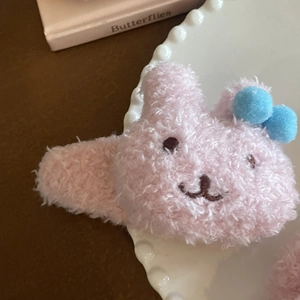 Detalle de una pinza para el pelo de conejo de felpa rosa con pompones azules