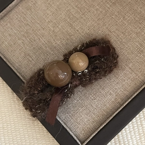 Detail of cute chocolate hazelnut hair clip with brown knits and shiny resin beads