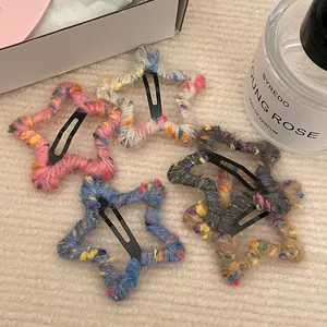Detailed close-up of five colorful knitted star-shaped hair clips on a soft beige fabric