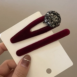 Set of two burgundy velvet hair clips with a chic woven ball decoration on a display card