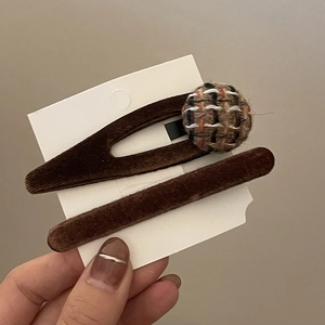 Detail of velvet hair clips with checkered tweed button and plush brown texture finish