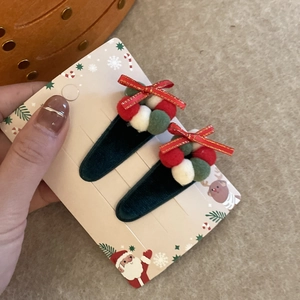 Détail de pinces à cheveux de Noël en velours vert avec mini-couronnes et nœuds rouges