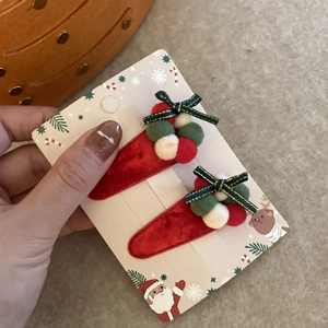 Détail de barrettes de Noël en velours rouge avec pompons et nœuds verts sur carte