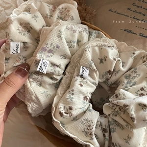 Close-up of floral scrunchies with lace trim and ribbed texture in vintage packaging