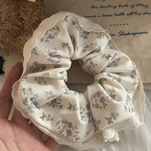 Detailed texture of cream floral scrunchie with elegant white lace trim for hair
