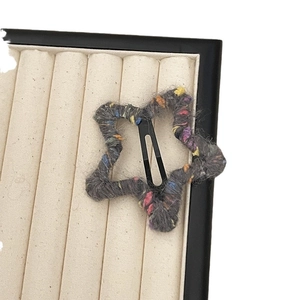 Star-shaped hair clips with colorful knit texture on a beige jewelry display tray
