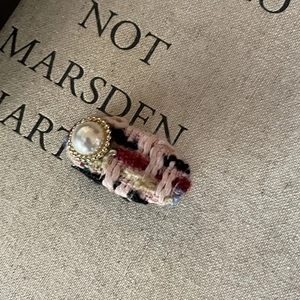 Detail shot of vintage tweed hair clip with a faux pearl in a golden floral setting