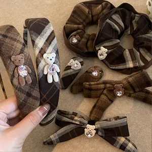 Détail d'accessoires cheveux à carreaux marron avec ours en peluche et strass en cœur