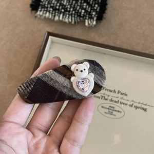 Détail d'une pince à cheveux à carreaux vintage avec ours en peluche et cristal cœur rose