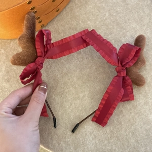 Détail d'un serre-tête de Noël en peluche avec bois de renne et nœuds en satin