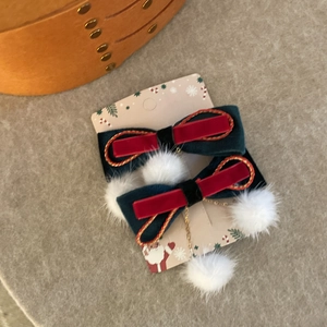 Détail de barrettes de Noël en velours avec pompons blancs et chaînes dorées sur carte