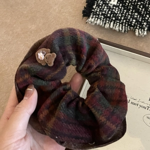 Gros plan d'un chouchou à carreaux avec ours en peluche et strass coeur violet