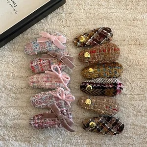 Close-up of assorted tweed bow hair clips with gold buttons on a soft beige texture