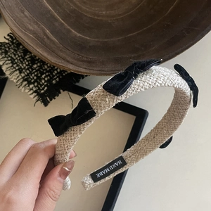 Detail of handmade beige woven headband featuring elegant black velvet bows