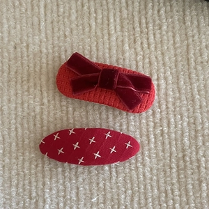 Detail of red knitted hair clip set with velvet bow and white cross-stitch embroidery