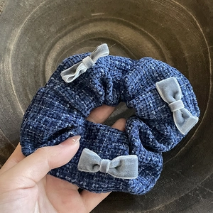 Detailed texture of blue knit scrunchie with three grey velvet bows for hair styling