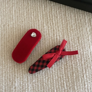 Detail of red velvet heart rhinestone hair clip and plaid bow clip on knit fabric