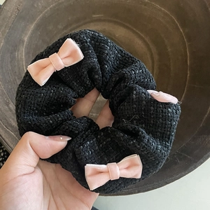 Elegant tweed scrunchie with three pink velvet bows shown in hand for high detail