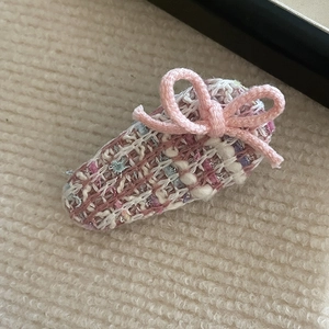 Pink tweed bow hair clip with elegant woven fabric for women on soft plush background