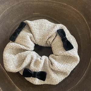 Elegant off-white tweed scrunchie with black velvet bows and subtle shimmering texture