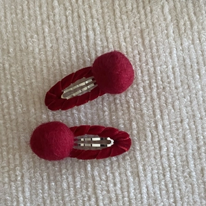 Close-up of red velvet hair clips with plush balls and metal BB clip base for girls