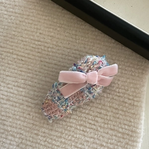 Close-up of a handmade colorful knit hair clip with a pink velvet bow decoration