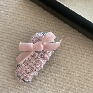Close-up detail of pink tweed bow hair clip with velvet texture on cream background
