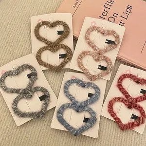 Detailed view of heart-shaped plush knit hair clips in assorted warm colors on card